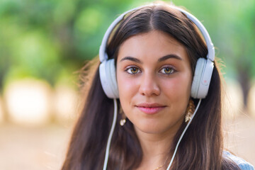 Pretty young woman listening to music in an oak forest.