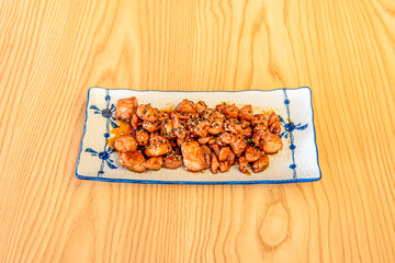 Japanese teppanyaki grilled fried chicken recipe with soy sauce and sesame and poppy seeds on wooden table