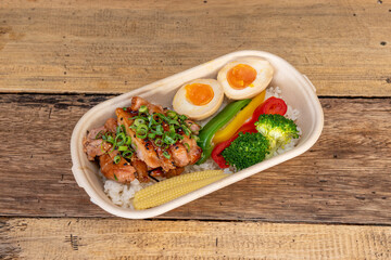 container of fried chicken takeaway with teriyaki sauce, boiled egg, tricolor pepper, broccoli and white rice with chives