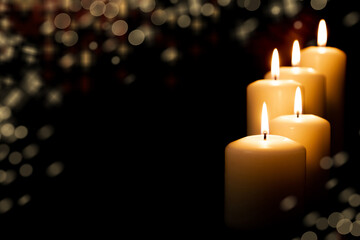 Burning candles on dark background. front view.