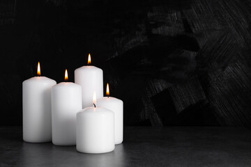 Burning candles on dark background. front view.
