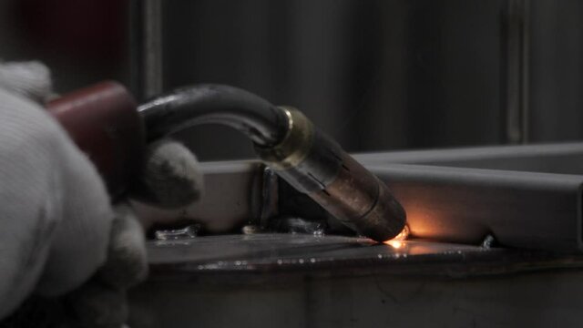 Closeup machine welding metal parts. Welder work welding torch flame light sparks metal worker hands. Steel welding tools equipment manufacturing process. Closeup metal construction plant. Metalwork