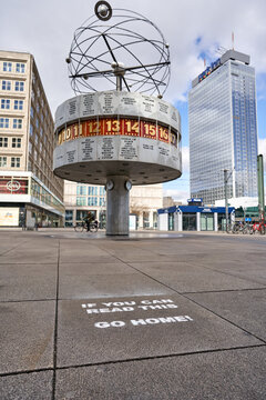 Berlin, Germany - 21.03.2020: view on the Urania World Clock on the deserted Alexander square, writing on the bottom: go home, people stay at home to reduce the risk of the corona virus 