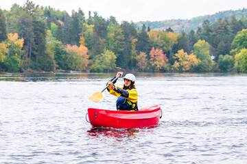 Fototapeta na wymiar A solo canoeist practices stroke techniques on a rainy fall day as part of a “moving water” paddling course. Shot on the Madawaska River an iconic paddling destination in Eastern Ontario, Canada.