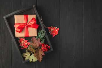 Christmas background with a gift box, wooden toys and branches on a black background.