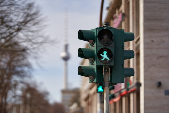 Berlin Germany 01.11.2021: cityscape, close-up of a green pedestrian traffic light at berlin with the blurred buldings, trees and tv-tower in the background