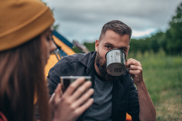 Couple of campers drinking coffee from a metal cups