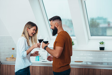 Beautiful couple drinking wine in the kitchen at home