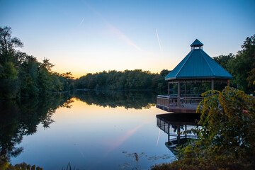 A gazebo looks out over the calm waters of Mill Pond in Milton during the late sunset.