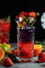 Colorful refreshing drinks for summer, cold strawberry lemonade juice with ice cubes in the glasses garnished with sliced fresh lemons