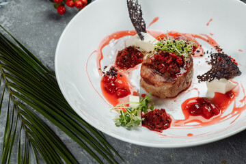 Appetizing beef in sweet sauce close up. Chopped beef meat in cherry sauce with vegetables on plate. Delicious european cuisine