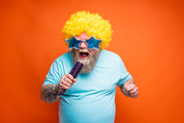 Fat man with beard, tattoos and sunglasses sings a song