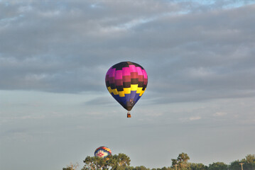Hot air balloon in flight with cloudy skies