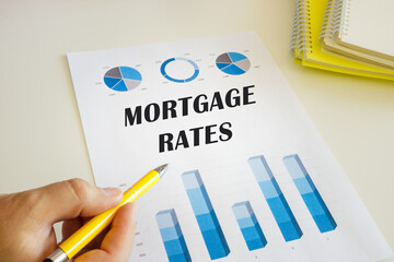 Business concept meaning MORTGAGE RATES with sign on the printout with diagrams and tables.