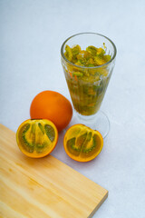 Lulada with lulos in halves on a marble background, tropical orange fruit