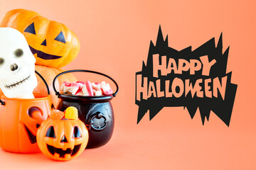 Happy Halloween decoration. Pumpkin, cauldron and gummy candies on orange background.