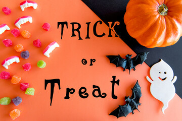 Happy Halloween decoration. Pumpkins, gummy candies, bats and ghost on orange background.