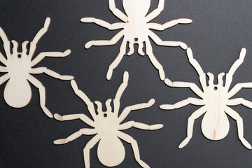 laser-cut halloween themed wooden shapes on a paper background - four spiders on black