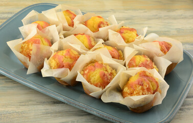 A Dozen lemon strawberry mini muffins in paper cups on blue brunch serving plate