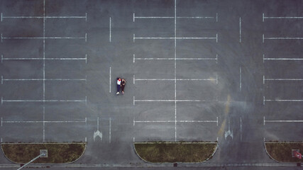 Young couple lying down on the shopping mall parking lot, drone shot from above