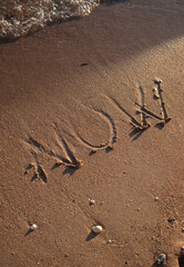 NOW sign in wet sand 
