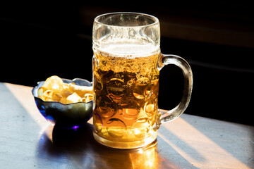 Large mug of beer and chips on a wooden table in a pub