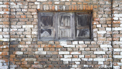 the old wooden window on the brown brick wall. the ancient portrait of the abandoned old building.