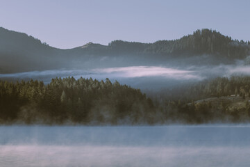 Landscape of Lake with trees and fog over the forest