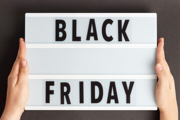 Female hands holding lightbox with the inscription Black Friday on background.
