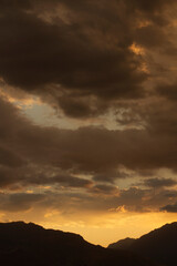 Cloudscape. Magical view of a dramatic sunset in the mountains. The beautiful sky, clouds and mountain dark silhouette with dusk colors.