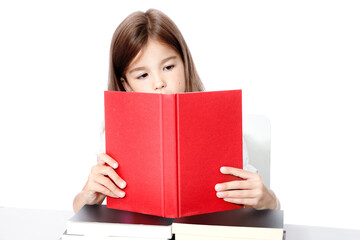 Young cute girl sitting at the table and reading a book