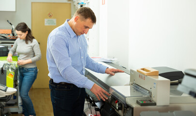 Man uses plotter in small printing shop. High quality photo