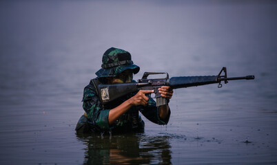 Soldier with weapon rifle on hand stayed in the water for protect from enemy.