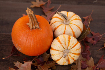 Small orange pumpkins on a table with leaves