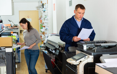 Printing company employees work on various printing machines. High quality photo