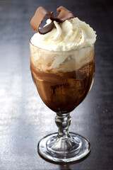 Bebida gelada de chocolate e creme chantilly com raspas de chocolate no fundo de madeira.