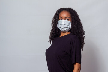 Mulher negra jovem com cabelos cacheados usando máscara contra covid