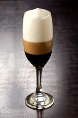 Bebida gelada preparada com café e leite na taça em fundo de madeira.