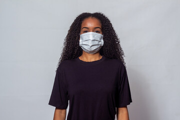 Mulher negra jovem com cabelos cacheados usando máscara contra covid