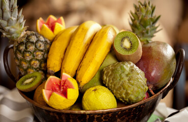 Cesta de frutas, banana, kiwi, goiabas, abacaxi, manga e atemoia em foco seletivo
