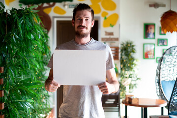 young man holding a white frame with copy space for text