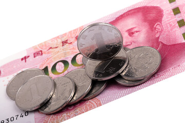 Several 1 Chinese yuan coins against the background of a 100 yuan banknote with a portrait of Chairman Mao