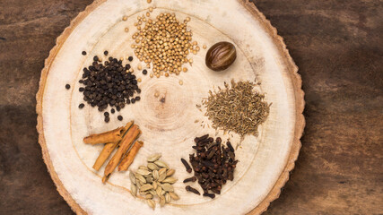 various spices used for cooking, simple indian garam masala ingredients, common blend of spices in south asian cuisines, on a wooden surface - obrazy, fototapety, plakaty