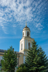 Fototapeta na wymiar The bell tower of the church against the sky and fir trees