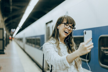 Woman having a video call at a subway platform, vivid tone