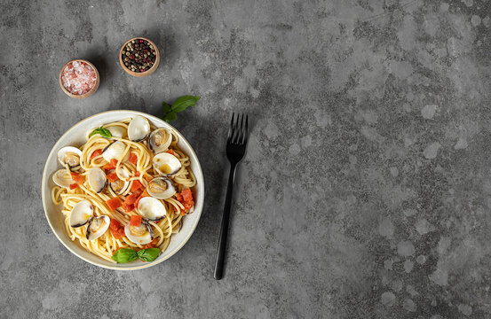 Spaghetti pasta with steamed clams. Fresh cooking Italian seafood recipe with tomatoes, garlic, and white wine. copy space.