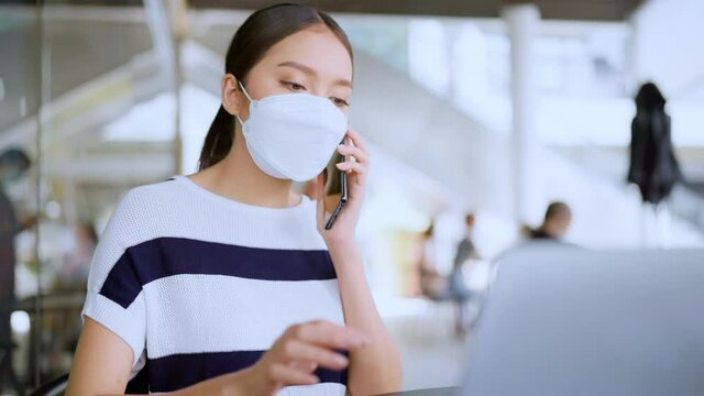 young attractive asian female wear casual cloth and face mask protecting hand use smartphone and laptop device comminication social contact in cafe restaruant outdoor freelance working lifestyle 