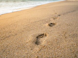 Footprints on the sandy beach and the sun is going down
