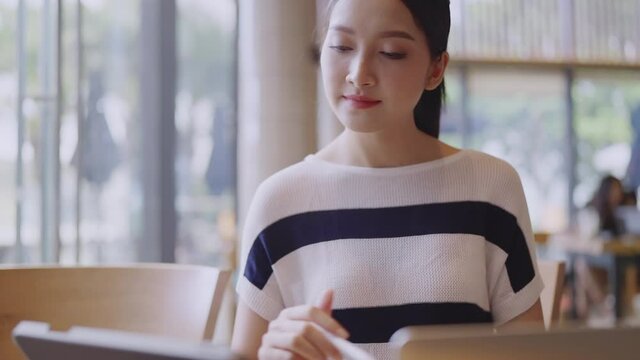 young attractive asian female wear casual cloth hand use smartphone and laptop device comminication social contact in cafe restaruant sit at counter next to big window daylight