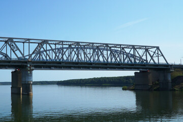 Fototapeta na wymiar Span of a bridge bridge over the river against the background of the blue sky.